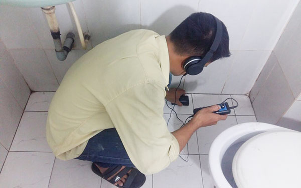 Kỹ thuật viên đang sử dụng máy siêu âm hiện đại để dò tìm vị trí rò rỉ nước ngầm trong đường ống